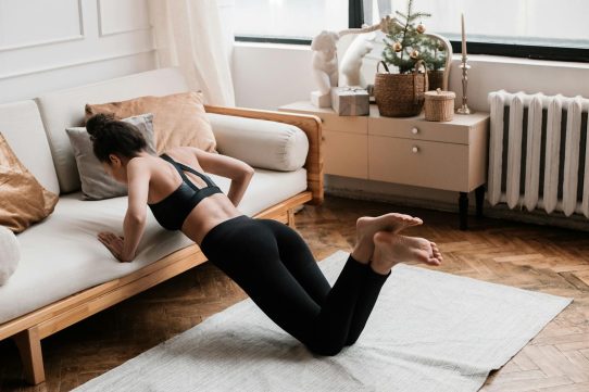 A woman stretches on a mat in a stylish living room, promoting a healthy lifestyle.