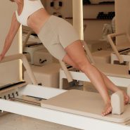Woman does pilates on a machine in a studio.