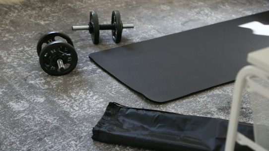 a pair of dumbbells and a black mat on the floor