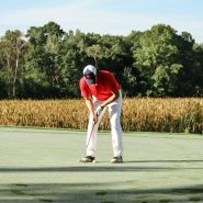 a man in a red shirt and white pants playing a game of golf