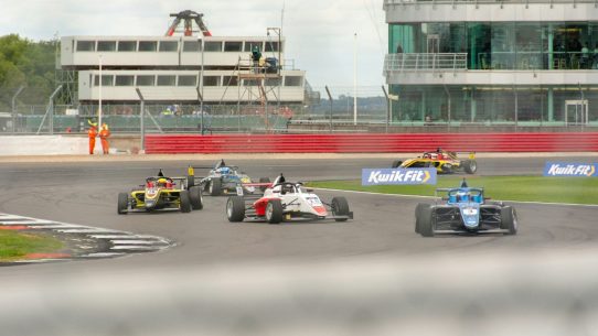 a group of racing cars driving down a race track