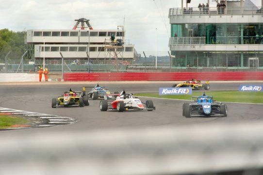 a group of racing cars driving down a race track
