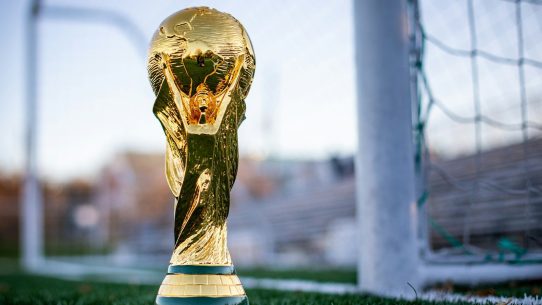 a golden soccer trophy sitting on top of a field