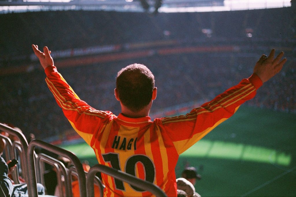 A man in an orange and yellow uniform at a soccer game