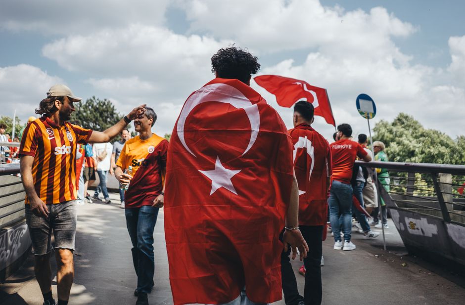 Outdoor scene of people celebrating with Turkish flags on a sunny day.