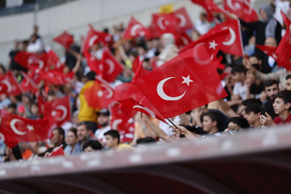 Vibrant crowd waving Turkish flags at a stadium gathering in Mersin, Türkiye.