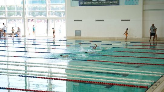 Kapalı yüzme havuzunda sporcular kulvarlarda yüzerken