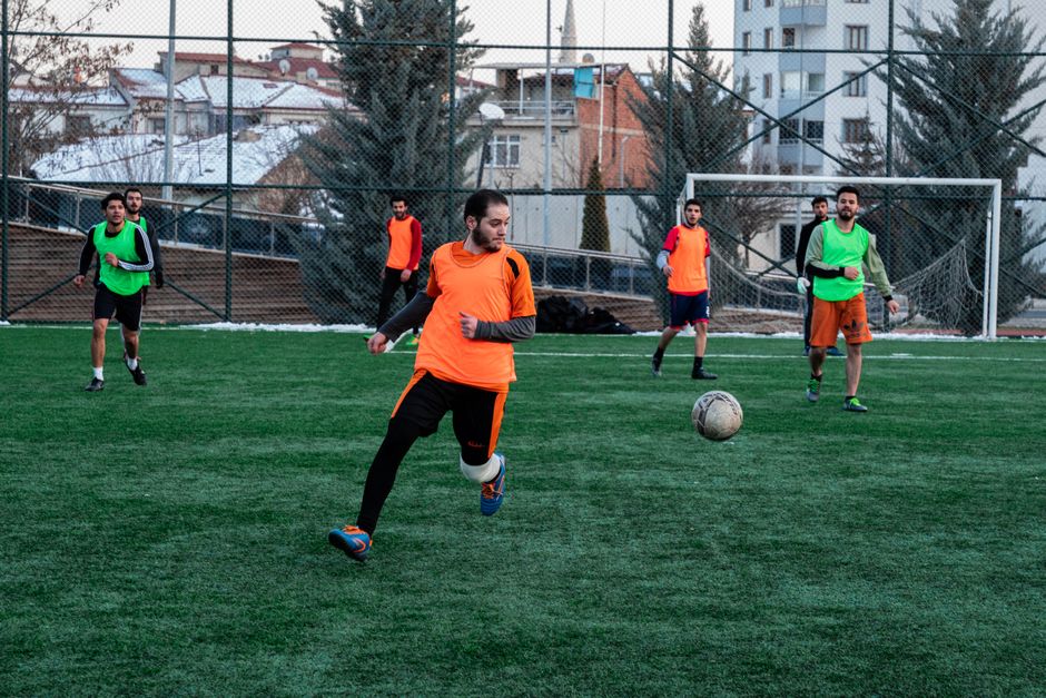 Men playing football on a field in İstanbul during team practice session.