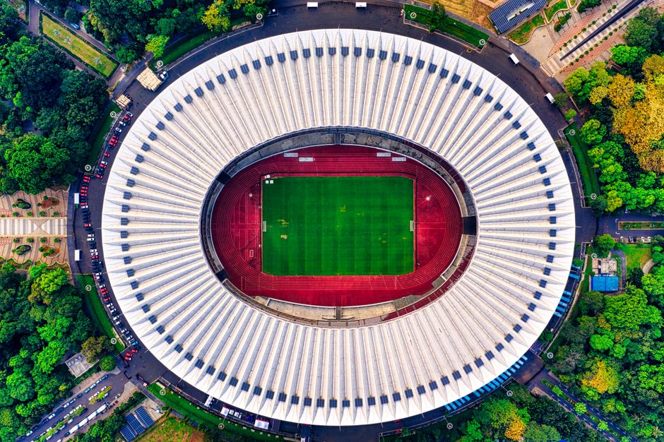 Drone shot of Gelora Bung Karno Stadium, showcasing its distinctive architecture and surrounding greenery.