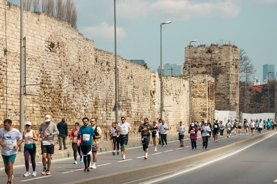 A dynamic scene of marathon runners beside ancient walls in Istanbul, Turkey.