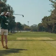 Bir golfçü ağaçlarla çevrili sahada vuruş yaparken
