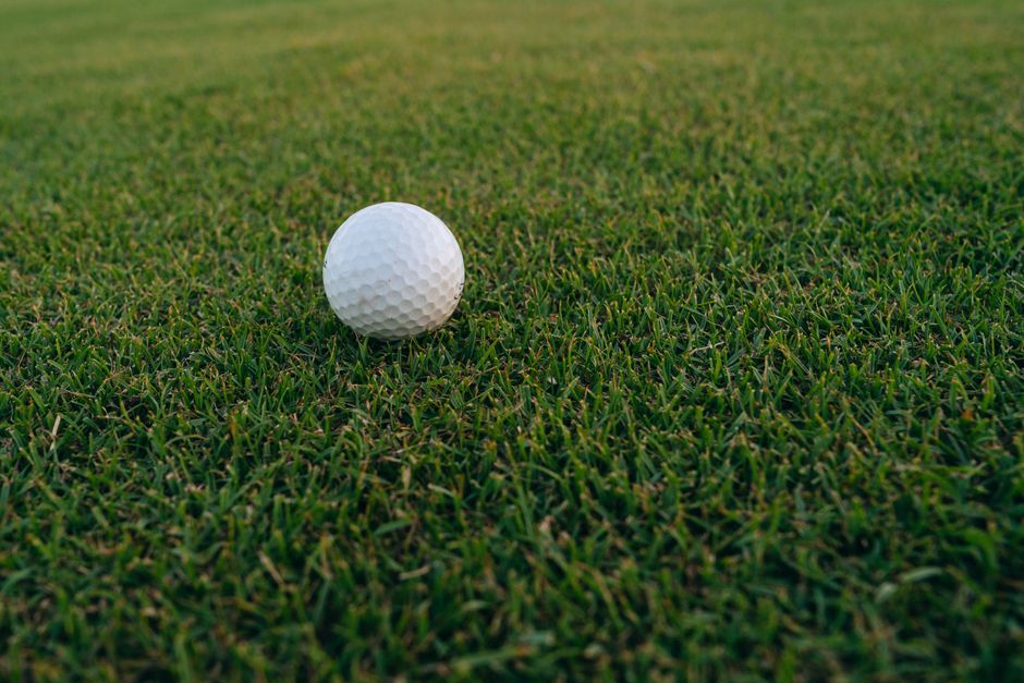 A close-up image of a golf ball resting on vibrant green grass, perfect for sports and recreation themes.