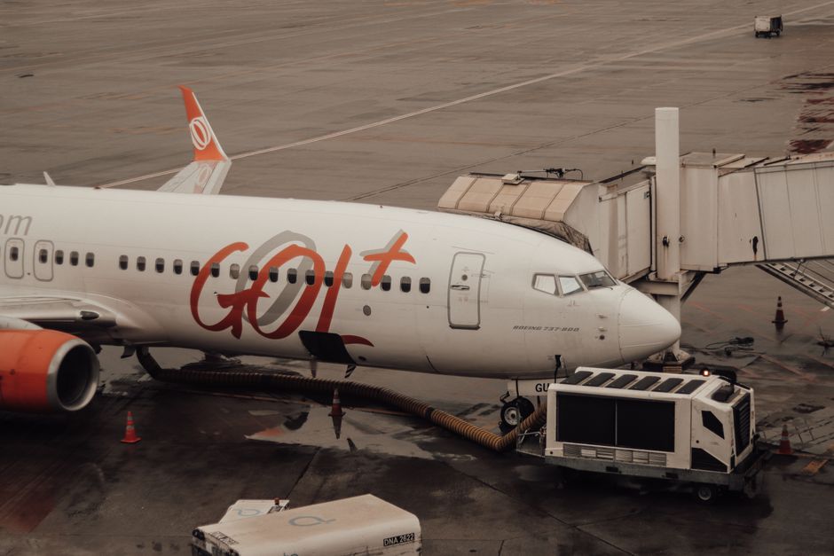 GOL Airlines aircraft connected to jet bridge at a wet airport terminal.