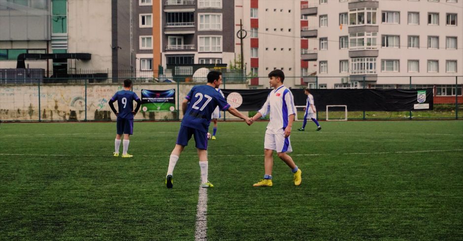 Soccer players shaking hands on an urban pitch in Tirebolu, Türkiye.