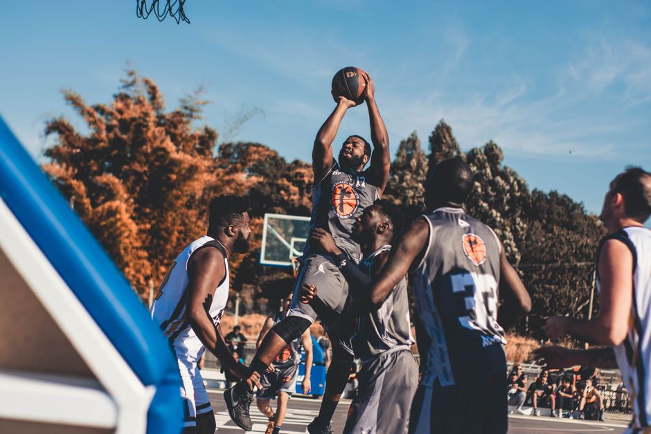 Dynamic basketball players in action during an outdoor game in a sunny park.