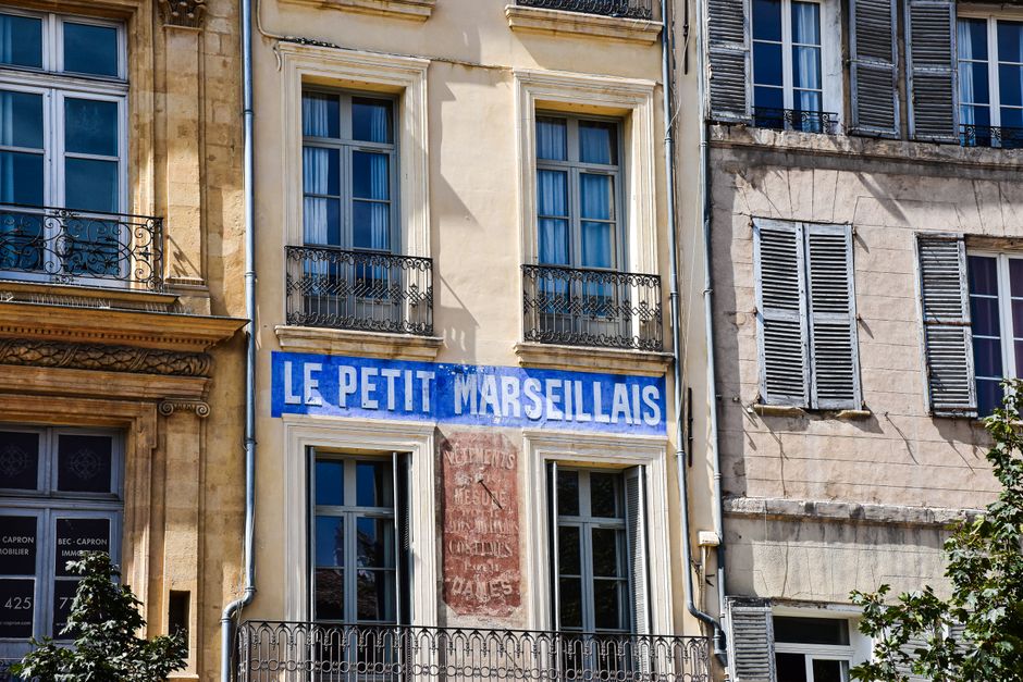 Charming building front with 'Le Petit Marseillais' in Aix-en-Provence, France.