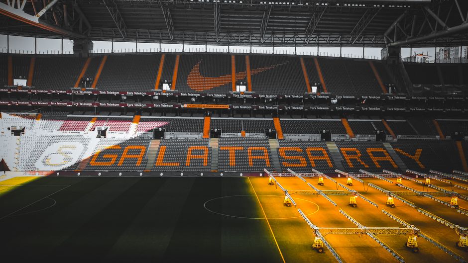 Interior view of Galatasaray Stadium in Istanbul featuring team logo and seating area.