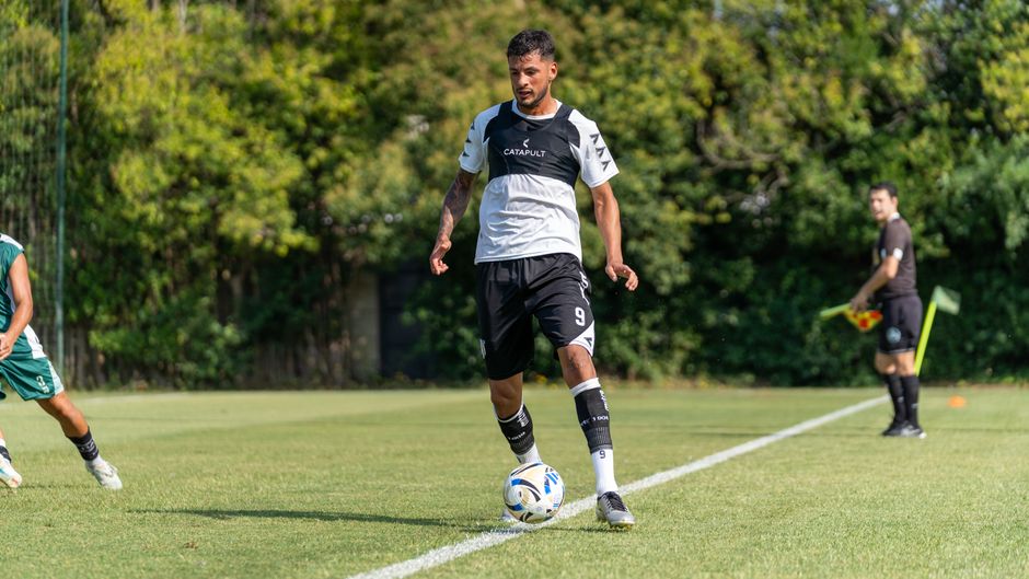 A soccer player in action dribbling the ball on a sunny outdoor field.