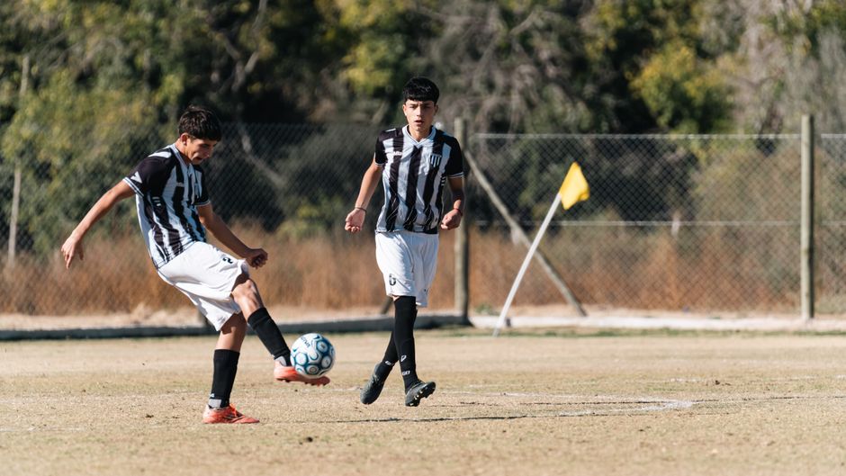 Two teenage players in action on an outdoor soccer field, sunny day.